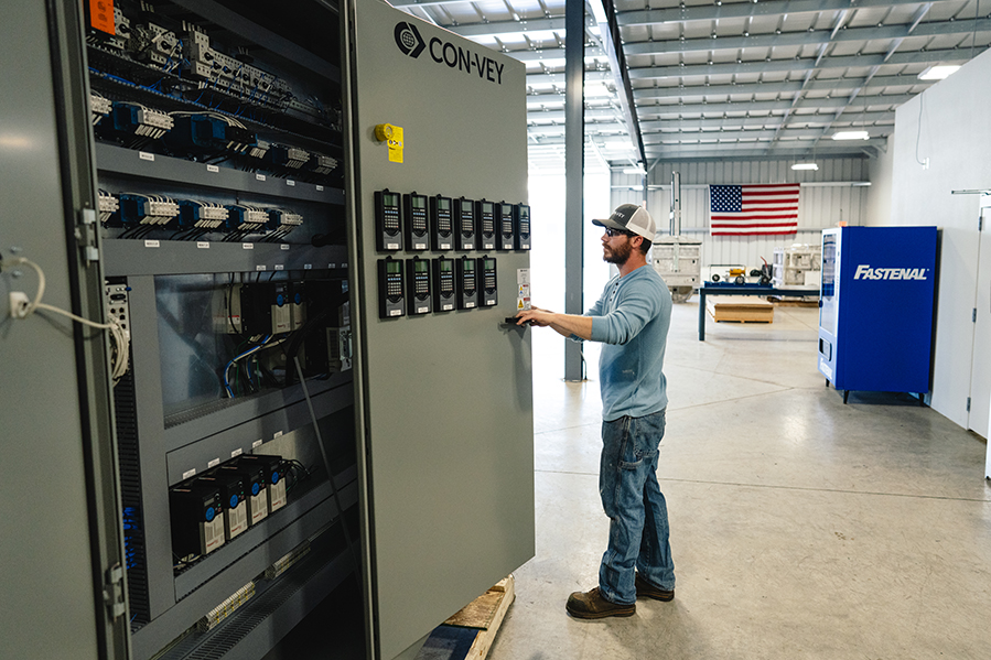 Con-Vey journeyman electrician standing by electrical control panel cabinet plc programmable logic controller mcc motor control center panel mcp engineered designed and manufactured for automated equipment by electrical engineers at certified panel fabrication shop in roseburg oregon usa.